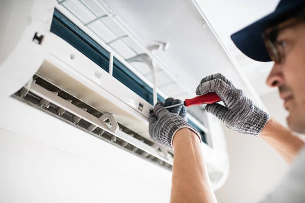 Technician working on the open air outlet of an indoor air conditioning unit