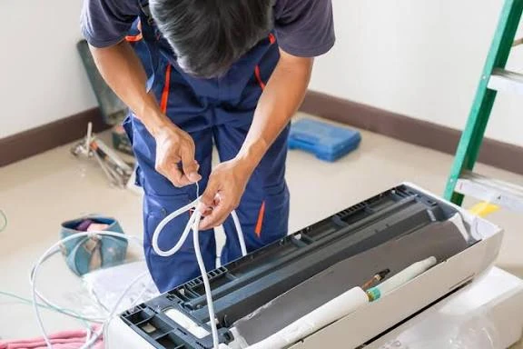 Technician checking wiring inside a disassembled indoor HVAC unit