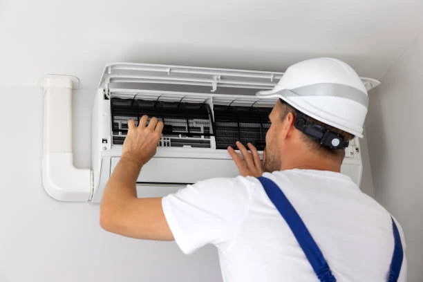Technician inspecting filters in a wall-mounted air conditioning unit