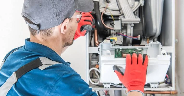 Technician inspecting the open controls of a heating unit