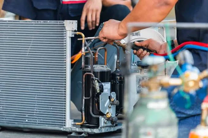 Hands repairing refrigerant piping and components inside an HVAC unit